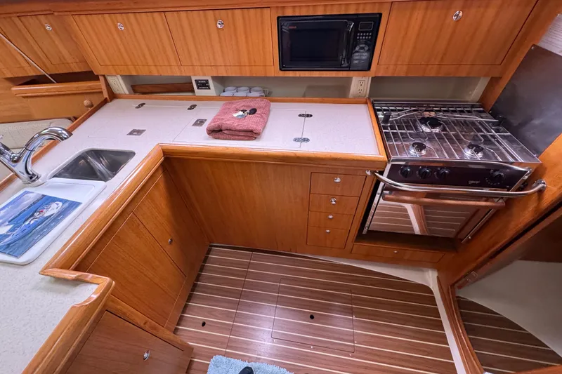 Slide: The Image of 2004 Hunter 386 yacht kitchen with wooden cabinetry, stove, sink, and microwave. - 10