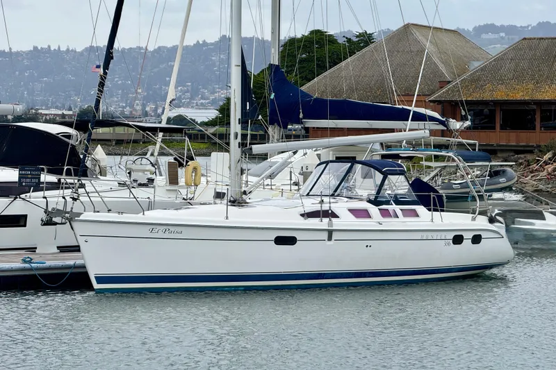 Slide: The Image of 2004 Hunter 386 sailboat docked in marina, featuring sleek design and spacious deck. - 2