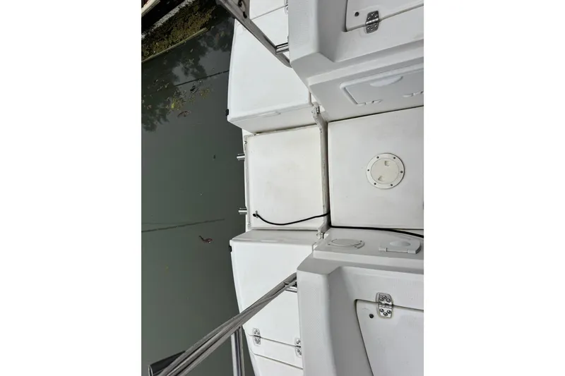 Slide: The Image of 2004 Hunter 386 boat deck with storage compartments and railing, docked on calm water. - 21