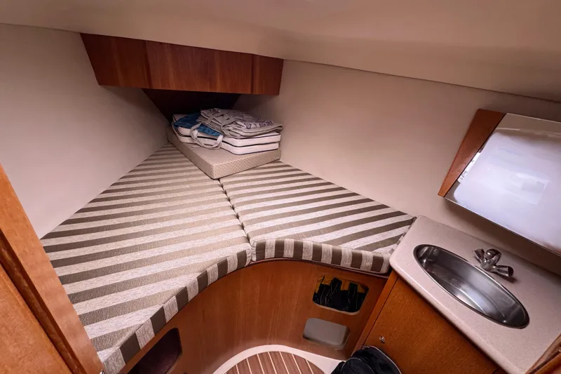 Slide: The Image of 2004 Hunter 386 yacht interior with striped bedding and compact sink area. - 7