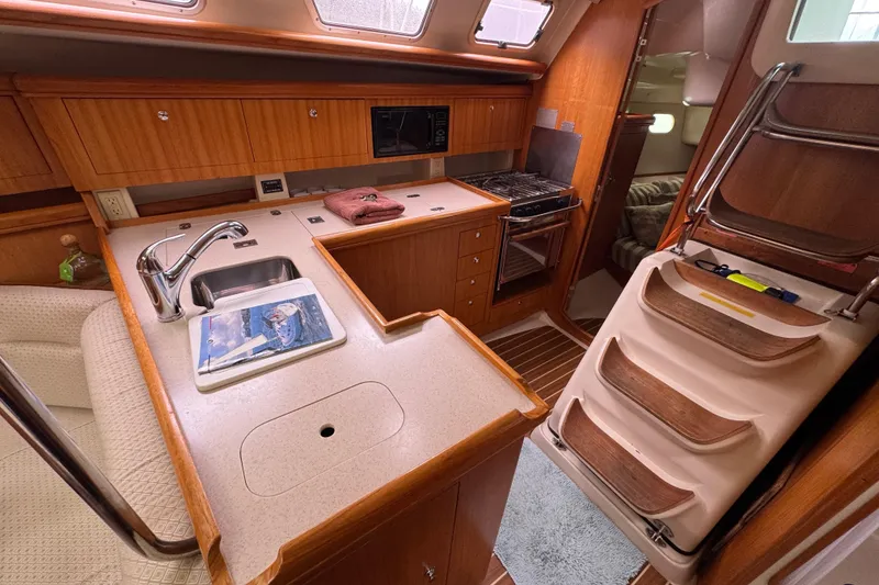 Slide: The Image of Interior of 2004 Hunter 386 sailboat kitchen with wood cabinetry and modern appliances. - 8