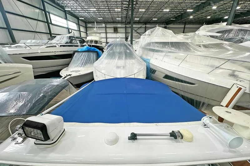 Slide: The Image of 2005 Formula 330 Sun Sport boat in storage, covered with blue tarp, surrounded by other boats. - 13