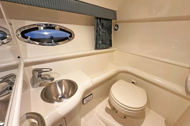 The Image of 2005 Formula 330 Sun Sport boat bathroom with sink, toilet, and porthole window. - 14