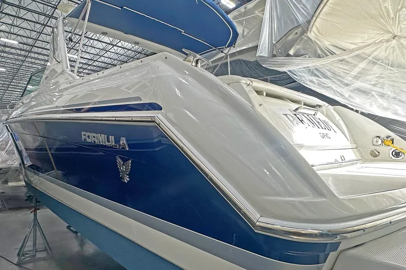Slide: The Image of 2005 Formula 330 Sun Sport boat in storage, featuring sleek blue and white design. - 2