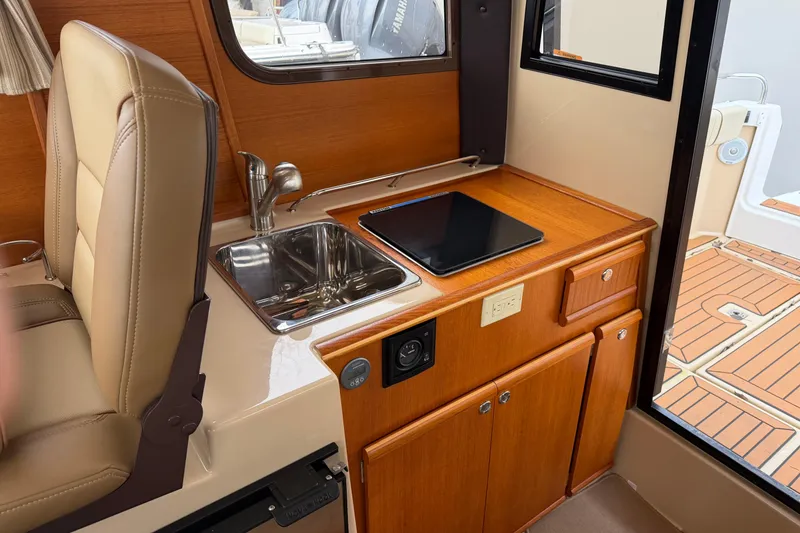 Slide: The Image of 2019 Ranger Tugs R-23 interior with compact kitchen, sink, and wooden cabinetry. - 4