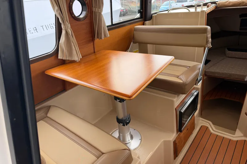 Slide: The Image of 2019 Ranger Tugs R-23 interior with wood table and beige seating. - 6