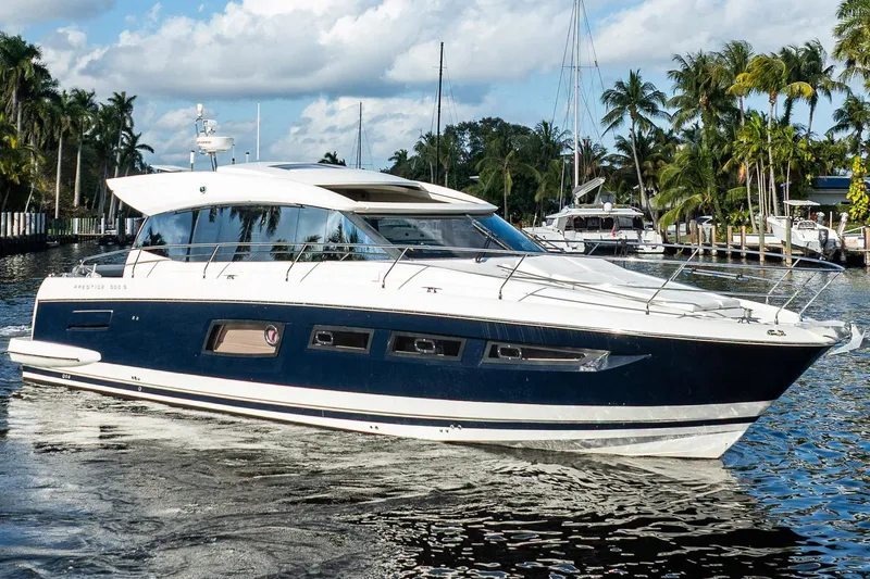 The Image of 2013 Prestige 500S yacht cruising on a sunny day, surrounded by palm trees and calm waters. - 2