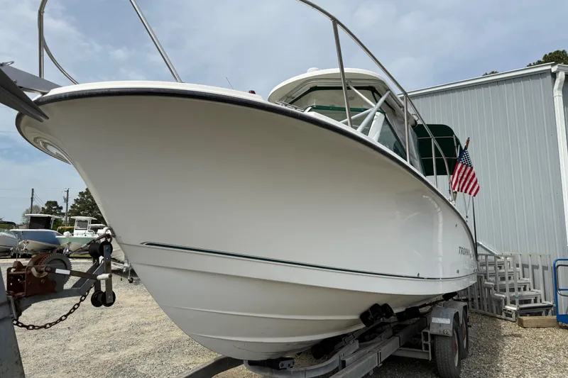 Slide: The Image of 2006 Trophy 2502 Walkaround boat on trailer, American flag displayed, parked outdoors. - 14