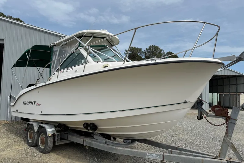 Slide: The Image of 2006 Trophy 2502 Walkaround boat on trailer, parked near a metal building. - 16