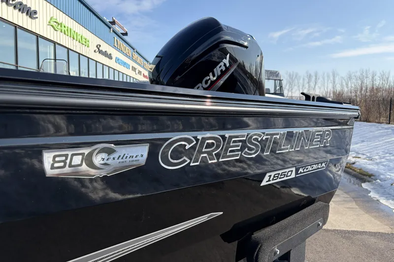 Slide: The Image of 2026 Crestliner 1850 Kodiak SC boat with Mercury engine, parked outdoors. - 23