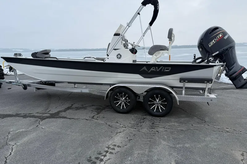 Slide: The Image of 2026 Avid 22 Recon boat on trailer with Yamaha motor, parked on a lakeside pavement. - 2