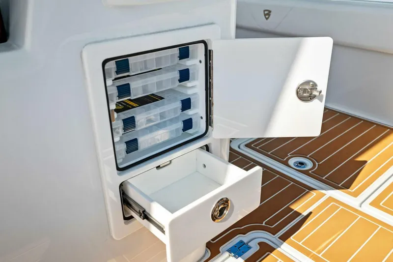 Slide: The Image of Open storage compartment on 2022 Barker Boatworks 40 HPC, featuring organized tackle boxes and drawer. - 23
