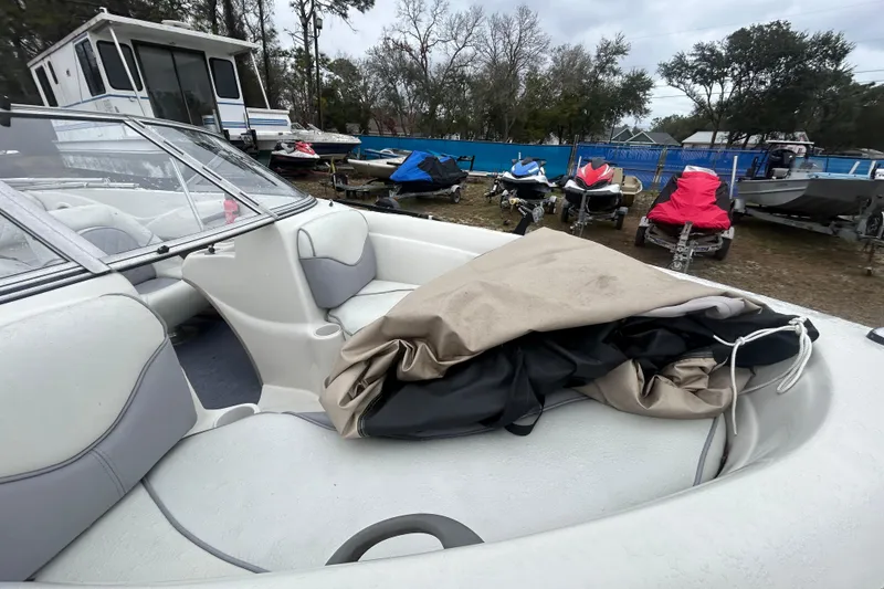 Slide: The Image of 2006 Tahoe Q4 boat interior with cover, parked near other boats and jet skis. - 13