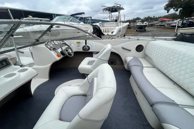 Slide: The Image of 2006 Tahoe Q4 boat interior with white seating and dashboard, docked at a marina. - 16