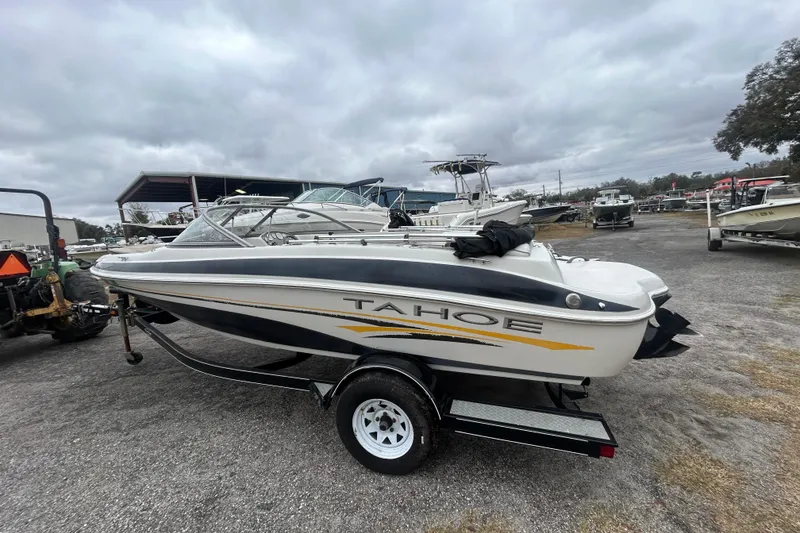 Slide: The Image of 2006 Tahoe Q4 boat on trailer, parked outdoors under cloudy sky. - 2