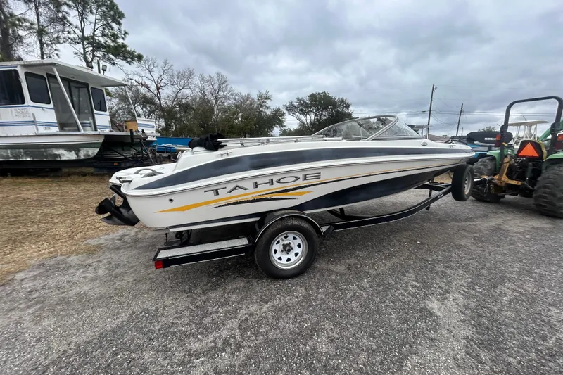 Slide: The Image of 2006 Tahoe Q4 boat on trailer, parked outdoors under cloudy sky. - 6