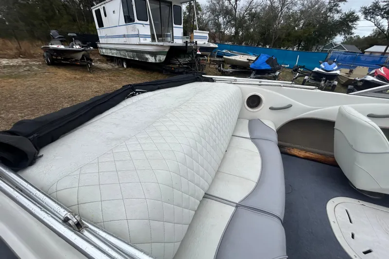 Slide: The Image of 2006 Tahoe Q4 boat interior with white quilted seats, parked near other boats. - 8