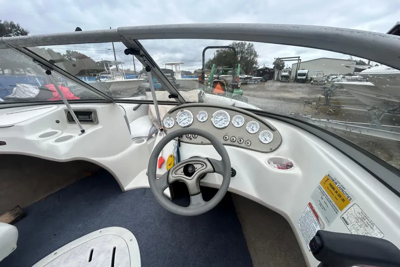 Slide: The Image of 2006 Tahoe Q4 boat dashboard with steering wheel and gauges, parked outdoors. - 9