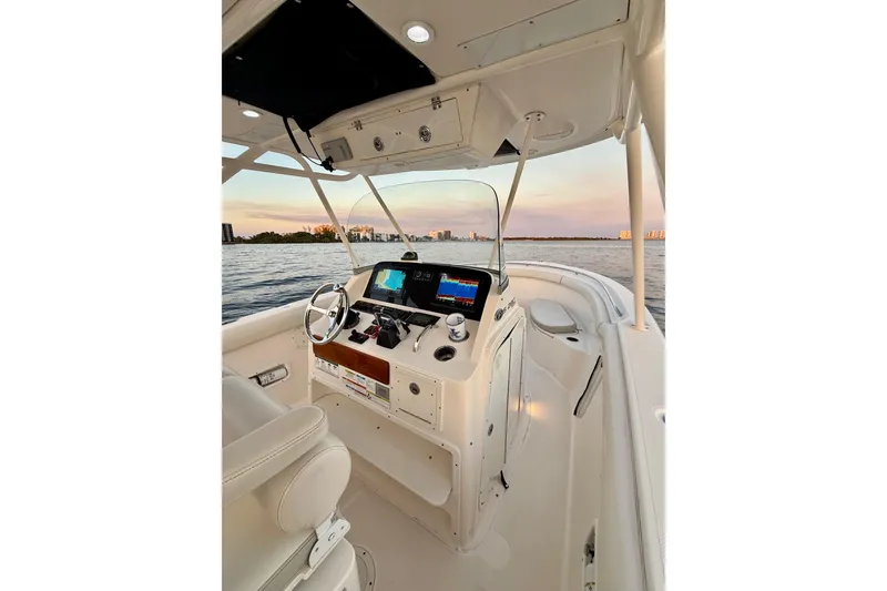 Slide: The Image of 2014 Pursuit S 280 Sport boat interior with steering console, on calm water at sunset. - 21