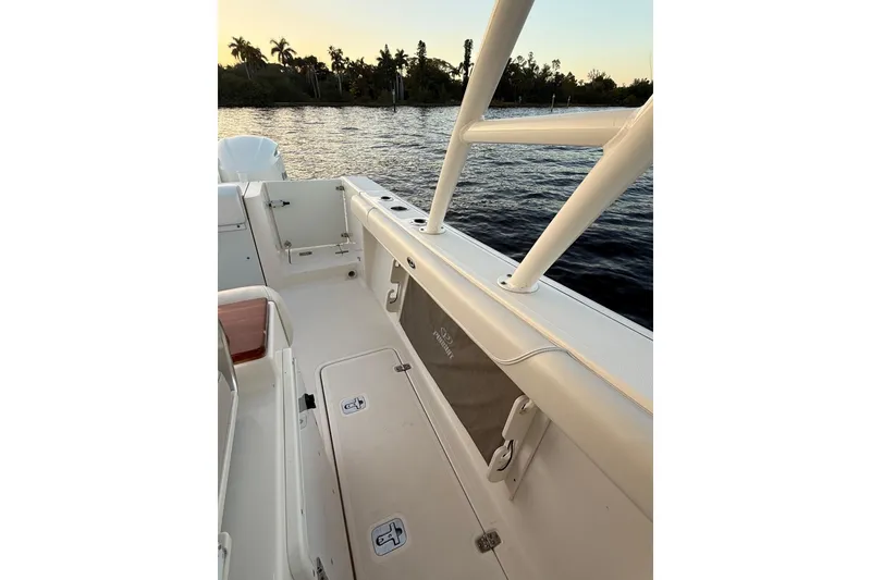 Slide: The Image of 2014 Pursuit S 280 Sport boat interior, featuring spacious deck and storage, near water at sunset. - 40