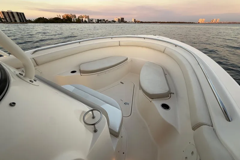 Slide: The Image of 2014 Pursuit S 280 Sport boat interior with cushioned seating, on calm water at sunset. - 44