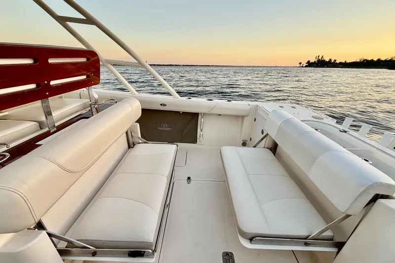 Slide: The Image of 2014 Pursuit S 280 Sport boat interior with white seating, ocean view at sunset. - 45