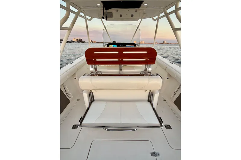 Slide: The Image of 2014 Pursuit S 280 Sport boat interior with seating, overlooking calm waters at sunset. - 46