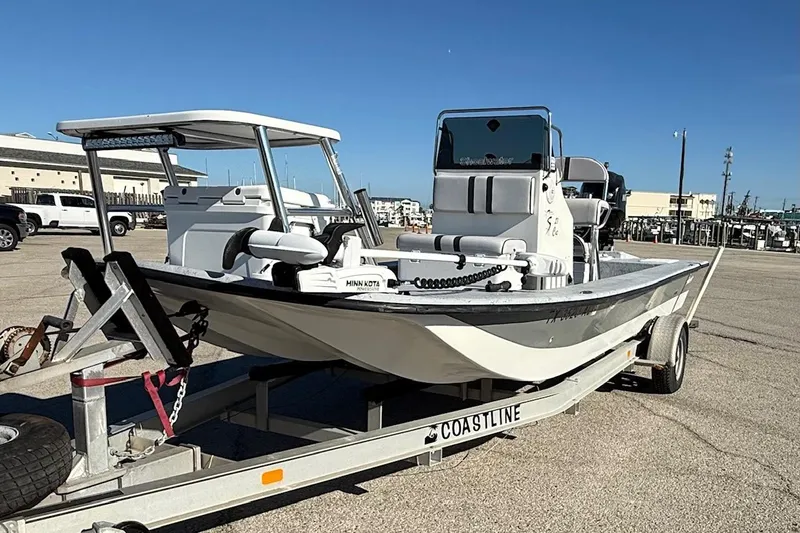 Slide: The Image of 2006 Shoalwater 21 Cat boat on trailer, parked in a marina lot under clear blue sky. - 6