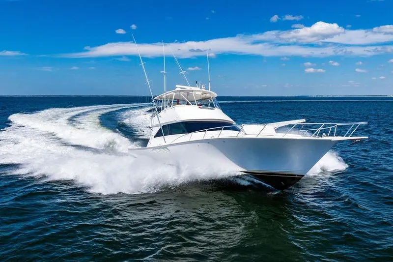 Slide: The Image of 2006 Viking 56 Convertible yacht cruising on open water under blue sky. - 11