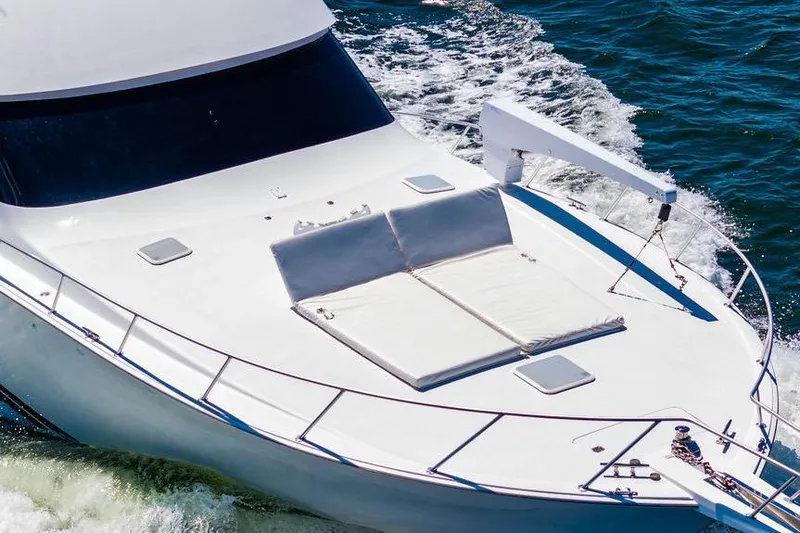 Slide: The Image of 2006 Viking 56 Convertible yacht cruising on open water, featuring a spacious deck. - 12