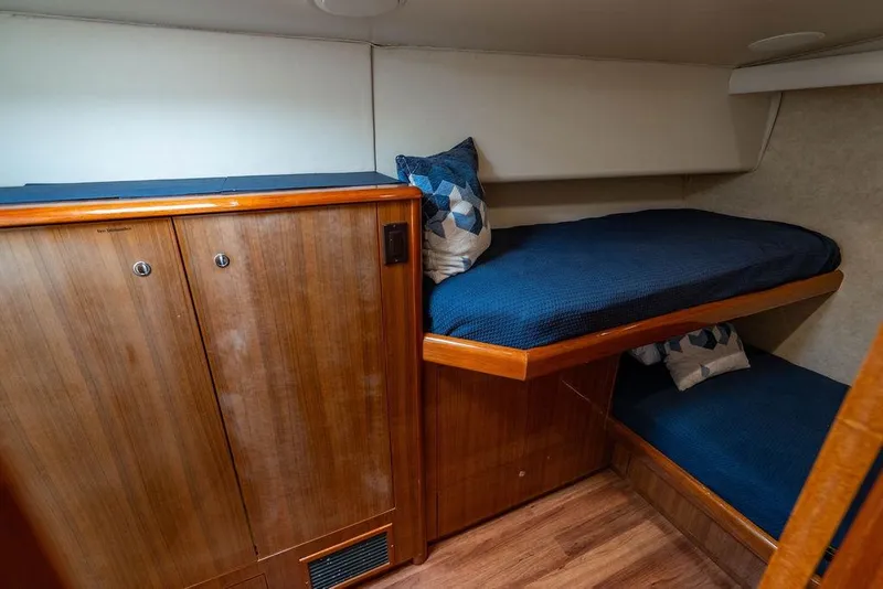 Slide: The Image of 2006 Viking 56 Convertible yacht cabin with wooden cabinetry and blue bedding. - 26