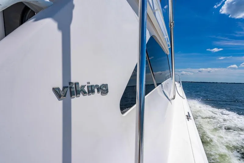Slide: The Image of 2006 Viking 56 Convertible yacht cruising on open water under blue sky. - 49