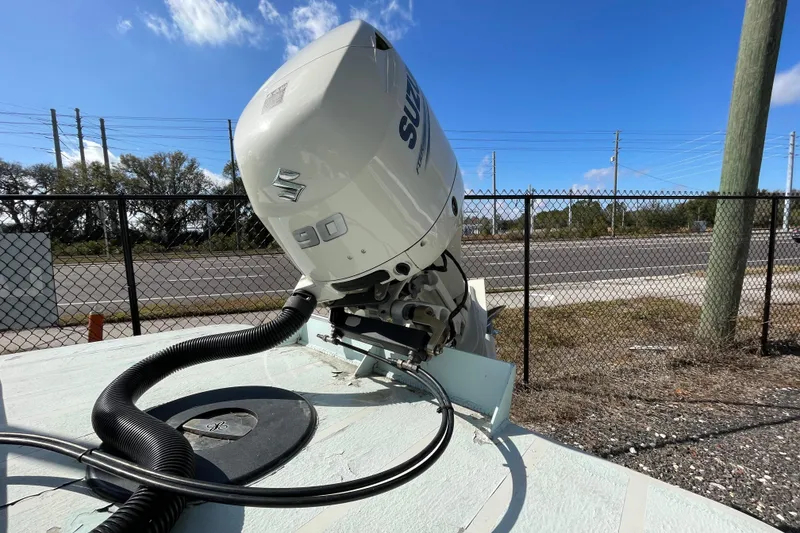 Slide: The Image of 1973 Mako 1901 Inshore boat with Suzuki 90 outboard motor, parked near a fence. - 3