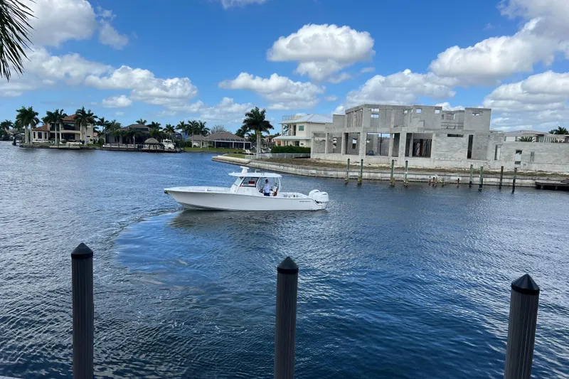 Slide: The Image of 2021 Sportsman Open 352 Center Console boat cruising near waterfront homes. - 53