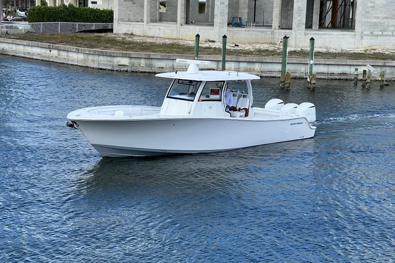 Slide: The Image of 2021 Sportsman Open 352 Center Console boat cruising on water near a dock. - 54