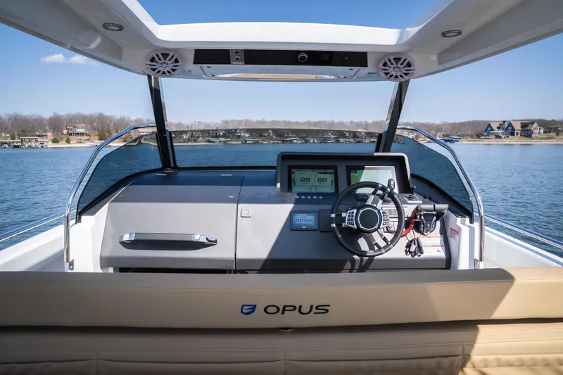 Slide: The Image of 2024 Opus OPUS 12 boat dashboard with steering wheel, on a serene lake. - 13