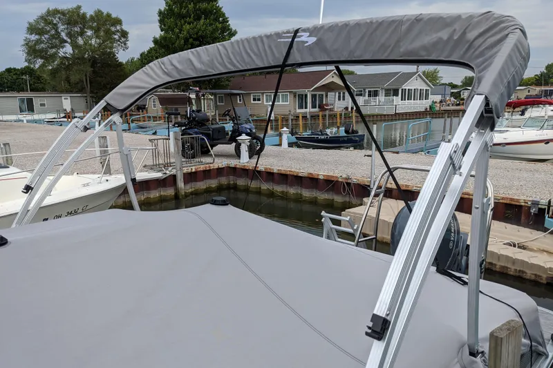 Slide: The Image of 2020 Bennington SXP 23 SSBXP pontoon boat docked at a marina with cover and canopy. - 14