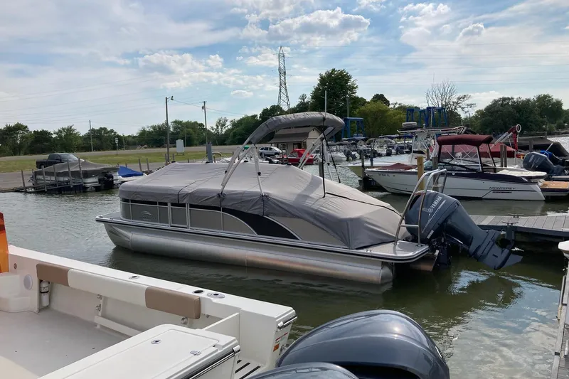 Slide: The Image of 2020 Bennington SXP 23 SSBXP pontoon boat docked with cover on, in a marina. - 16