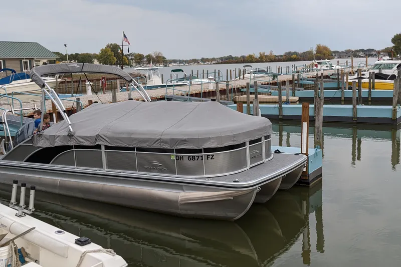 Slide: The Image of 2020 Bennington SXP 23 SSBXP pontoon boat docked with cover, calm marina setting. - 17