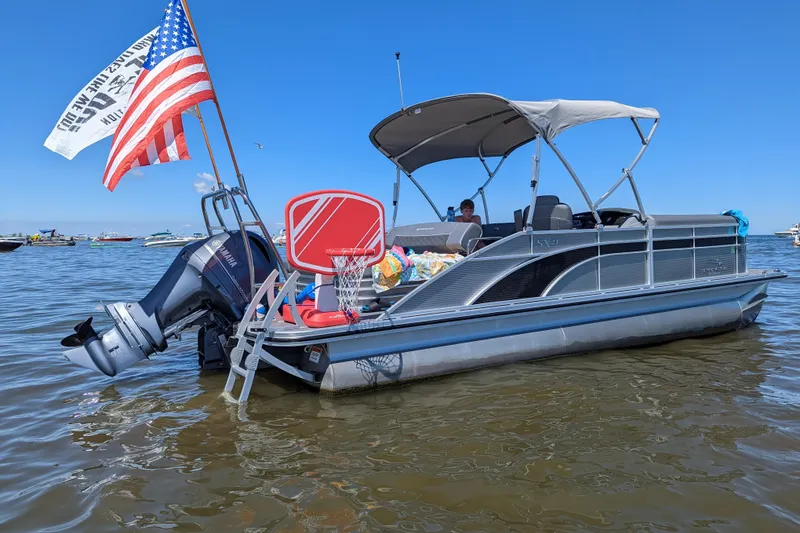 Slide: The Image of 2020 Bennington SXP 23 SSBXP pontoon boat with flags, anchored on a sunny day. - 2