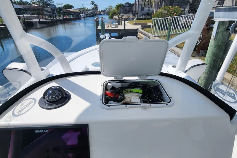 Slide: The Image of 2023 Sea Pro 248 Bay boat dashboard with open storage compartment, compass, and Simrad display. - 16
