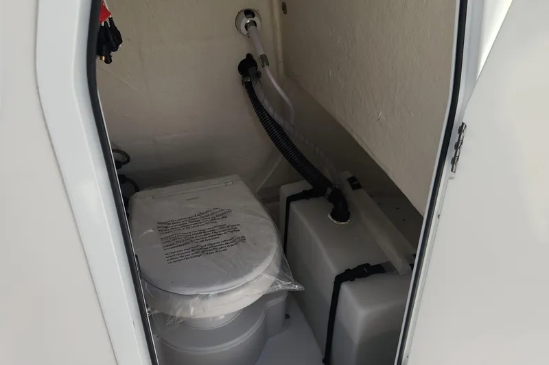 Slide: The Image of 2023 Sea Pro 248 Bay boat interior with compact marine toilet and storage compartment. - 23