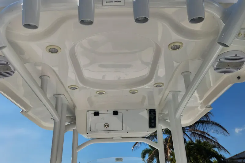 Slide: The Image of 2023 Sea Pro 248 Bay boat T-top with rod holders and speakers, under clear blue sky. - 32