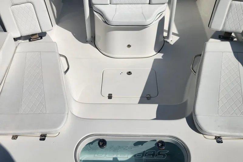 Slide: The Image of 2023 Sea Pro 248 Bay boat interior with white cushioned seating and storage compartments. - 34