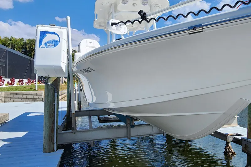 Slide: The Image of 2023 Sea Pro 248 Bay boat on lift, dockside view with clear sky. - 5
