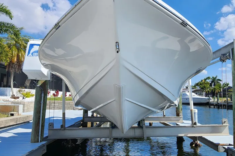 Slide: The Image of 2023 Sea Pro 248 Bay boat on lift, dockside with palm trees and blue sky. - 7