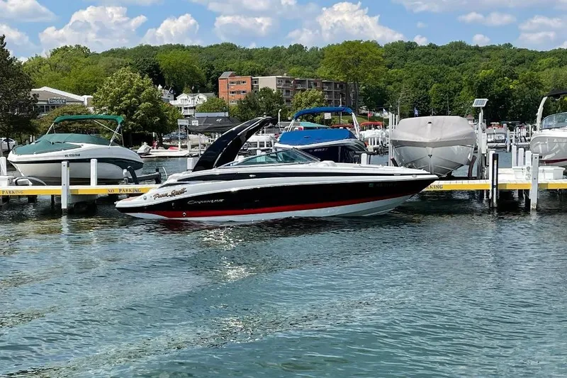 The Image of 2014 Crownline 255 SS boat docked at a scenic marina with lush greenery. - 0