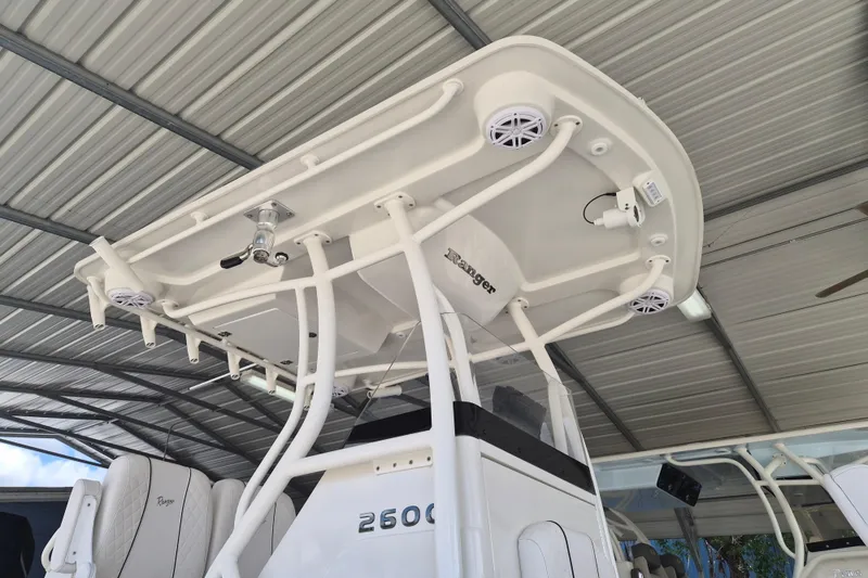 Slide: The Image of 2025 Ranger 2600 Bay boat with T-top and speakers under a metal roof. - 14