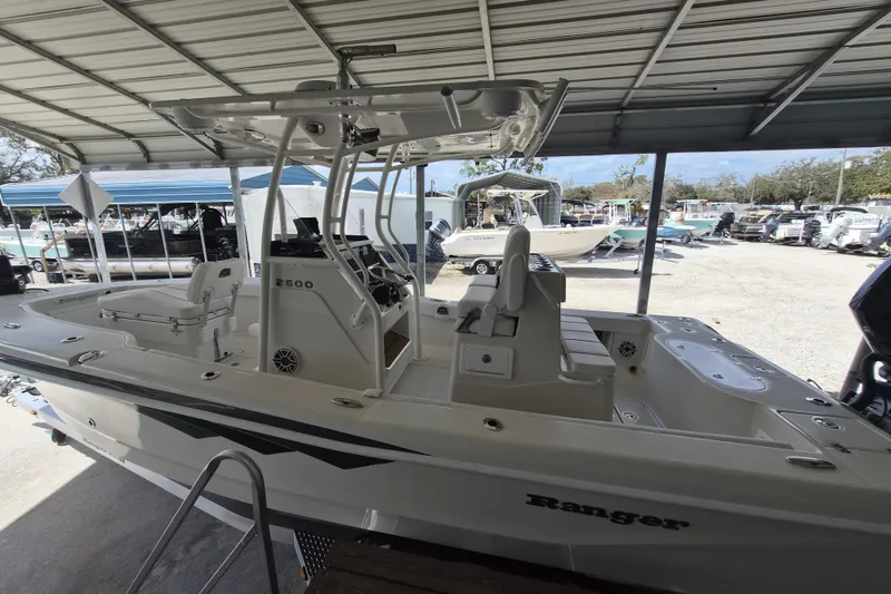 Slide: The Image of 2025 Ranger 2600 Bay boat under a metal canopy, showcasing sleek design and spacious interior. - 5
