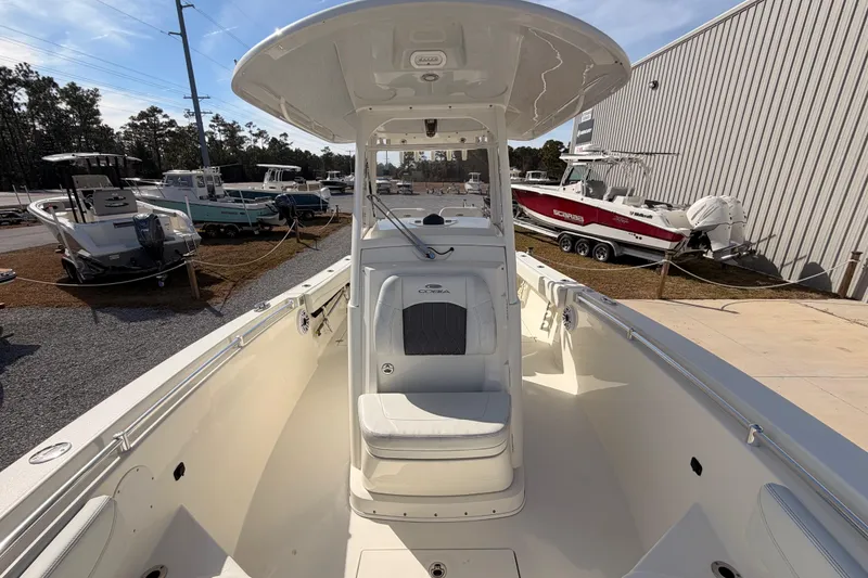 Slide: The Image of 2024 Cobia 262 Center Console boat, sleek design, parked outdoors at a dealership. - 13